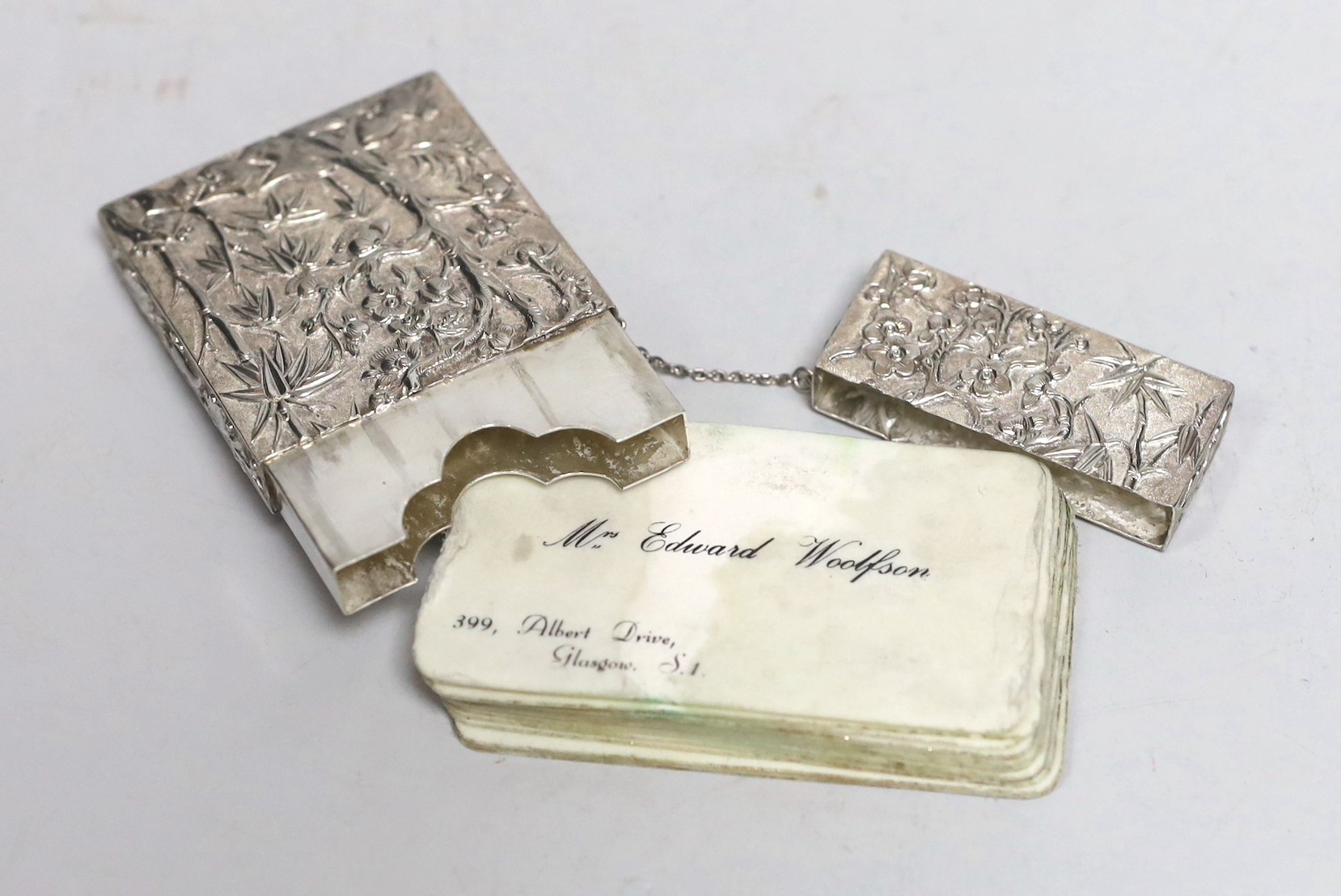 A 19th Chinese Export white metal rectangular card case, by Cutshing, stamped 'CUT', embossed with figured in garden scene and prunus tree, 78mm.